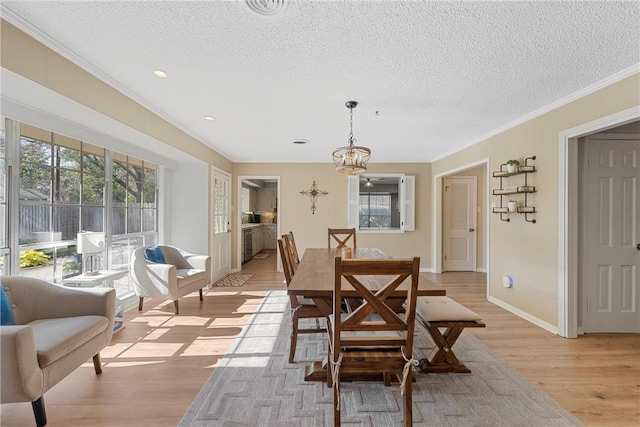 dining room with crown molding, a textured ceiling, and light wood-type flooring