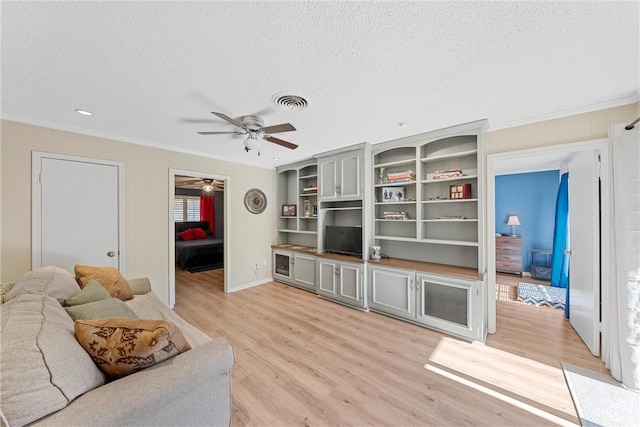 living room featuring light wood-type flooring, a textured ceiling, ceiling fan, and crown molding