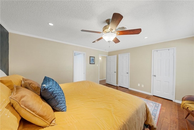 bedroom with ceiling fan, hardwood / wood-style floors, crown molding, and a textured ceiling