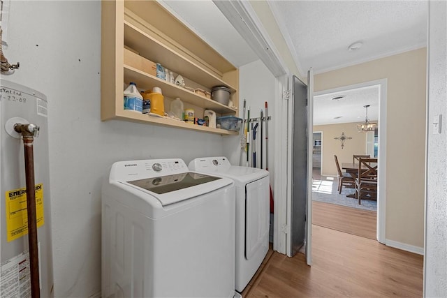 clothes washing area with an inviting chandelier, water heater, light hardwood / wood-style flooring, a textured ceiling, and washer and clothes dryer