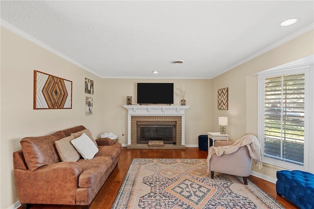 living room with a fireplace, hardwood / wood-style floors, a textured ceiling, and ornamental molding