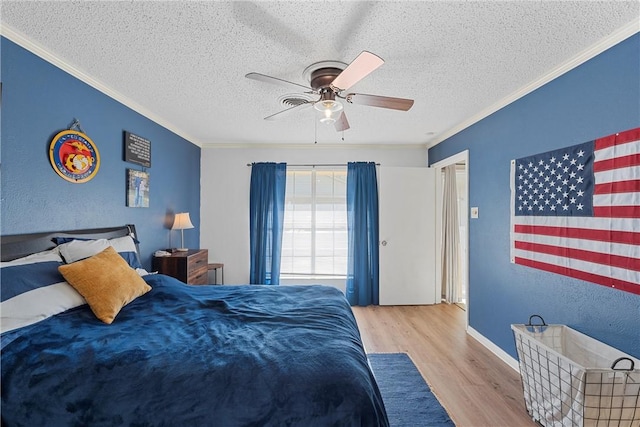 bedroom with a textured ceiling, light hardwood / wood-style flooring, ceiling fan, and ornamental molding