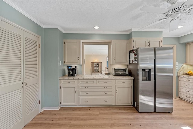 kitchen featuring crown molding, stainless steel fridge with ice dispenser, a textured ceiling, and light wood-type flooring