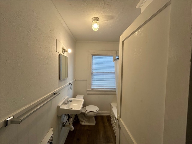 bathroom featuring a bathing tub, crown molding, toilet, a textured ceiling, and wood-type flooring