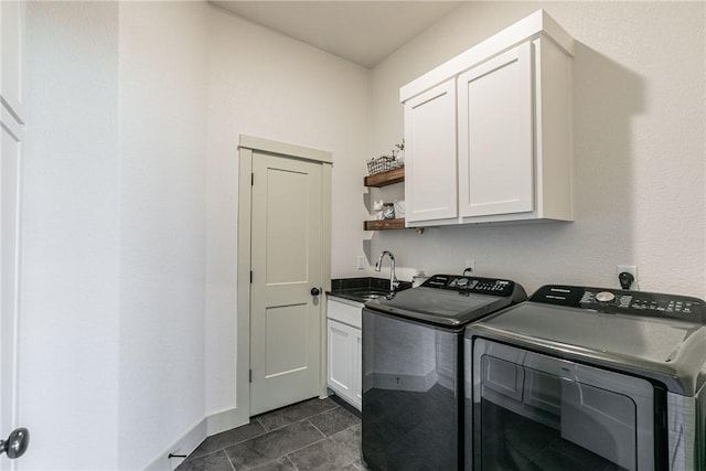 clothes washing area with dark tile patterned flooring, washer and dryer, cabinets, and sink