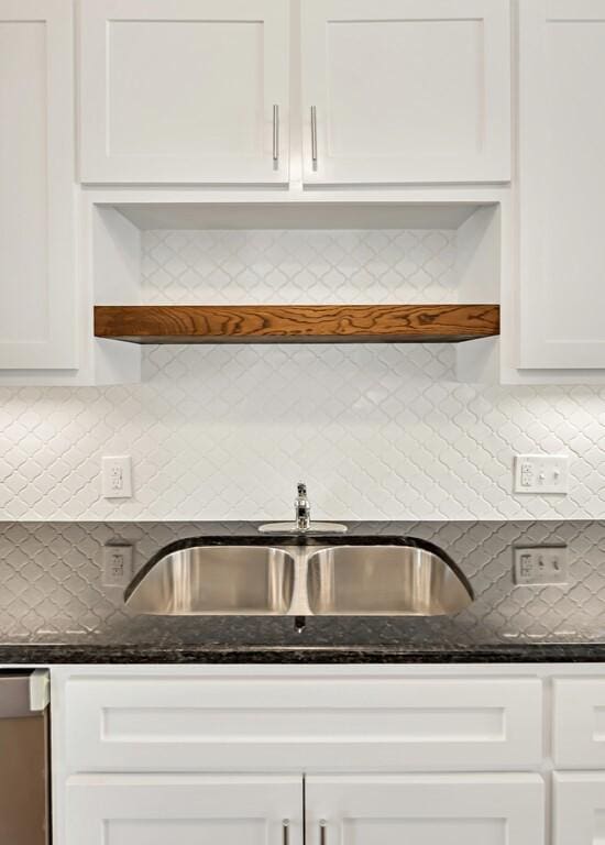 kitchen featuring backsplash, dark stone counters, sink, dishwasher, and white cabinets