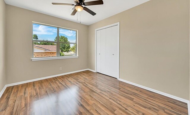 unfurnished bedroom with wood-type flooring, a closet, and ceiling fan