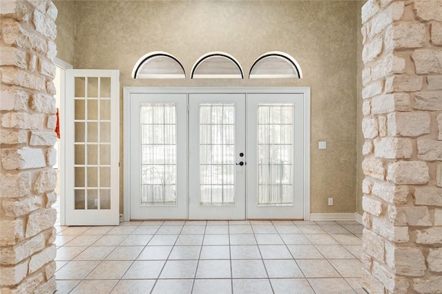 doorway featuring light tile patterned floors, a towering ceiling, and french doors