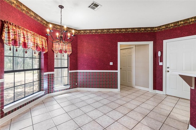 unfurnished dining area featuring a chandelier, tile patterned floors, and a wealth of natural light