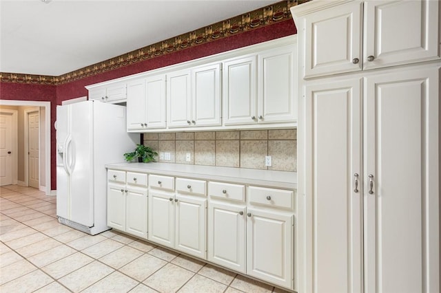 kitchen with white cabinets, decorative backsplash, white refrigerator with ice dispenser, and light tile patterned flooring