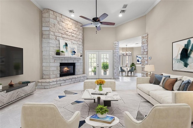 living room with a high ceiling, a stone fireplace, light carpet, ceiling fan with notable chandelier, and ornamental molding