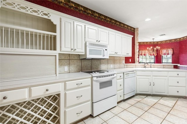 kitchen featuring white appliances, white cabinets, hanging light fixtures, light tile patterned flooring, and a chandelier