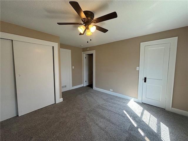 unfurnished bedroom with ceiling fan, a closet, a textured ceiling, and dark colored carpet