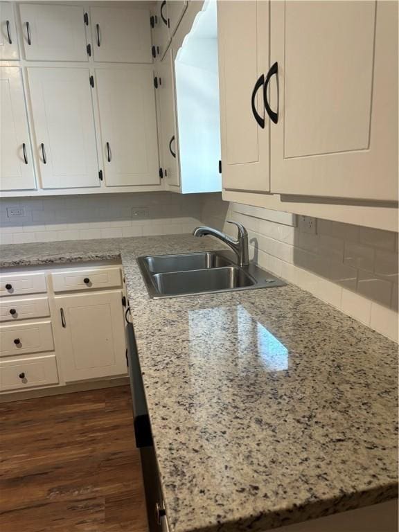 kitchen featuring sink, backsplash, white cabinets, dark hardwood / wood-style flooring, and light stone countertops