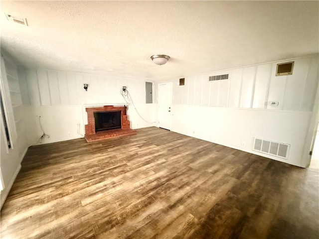 unfurnished living room with a fireplace, dark wood-type flooring, electric panel, and a textured ceiling