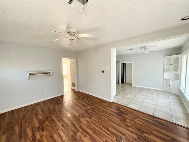 empty room featuring a textured ceiling, light hardwood / wood-style floors, and ceiling fan