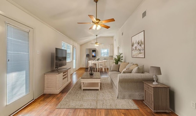 living room featuring ceiling fan, lofted ceiling, ornamental molding, and light wood-type flooring