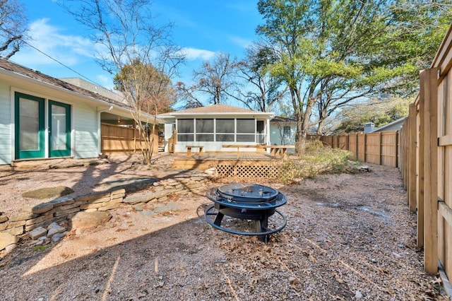 rear view of house featuring a sunroom and an outdoor fire pit