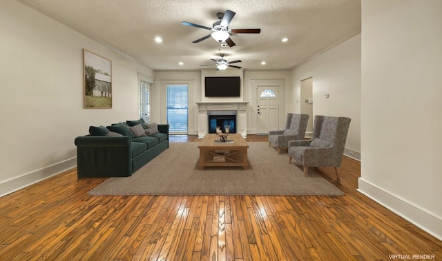 living room with a tiled fireplace, ceiling fan, wood-type flooring, and a textured ceiling