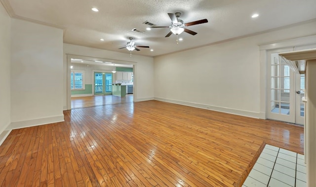 empty room with crown molding, ceiling fan, a textured ceiling, and light wood-type flooring