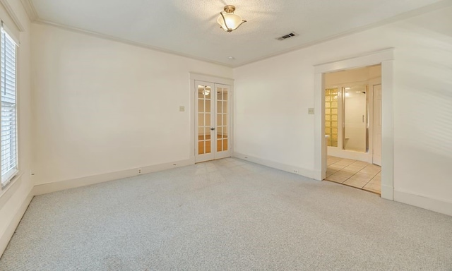 empty room with a textured ceiling, ornamental molding, french doors, and a healthy amount of sunlight