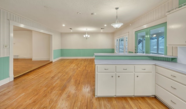 kitchen featuring white cabinetry, pendant lighting, light hardwood / wood-style floors, and a textured ceiling