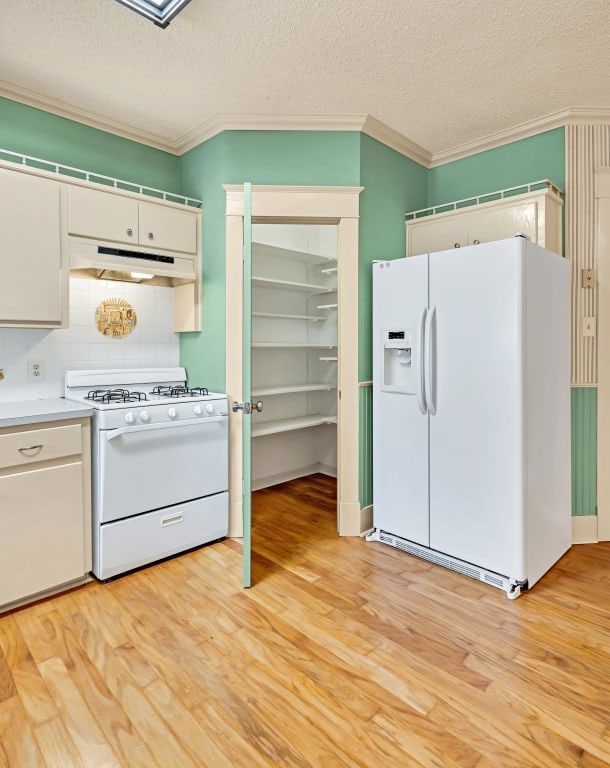 kitchen featuring white cabinetry, white appliances, light hardwood / wood-style floors, and a textured ceiling