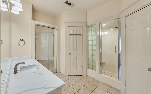 bathroom with a shower with door, an inviting chandelier, vanity, a textured ceiling, and tile patterned floors