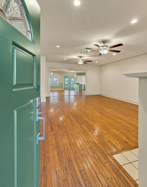 unfurnished living room featuring ceiling fan, wood-type flooring, and a textured ceiling