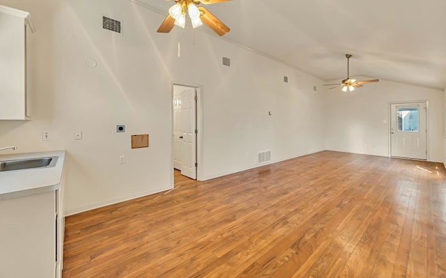 unfurnished living room with vaulted ceiling, sink, ceiling fan, and light wood-type flooring