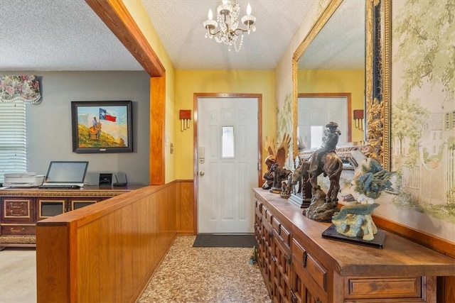 foyer featuring a healthy amount of sunlight, a textured ceiling, and an inviting chandelier