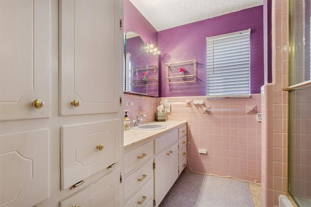 bathroom with a textured ceiling, vanity, and tile walls