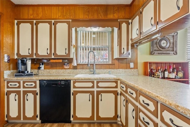 kitchen featuring kitchen peninsula, a textured ceiling, wooden walls, sink, and black dishwasher