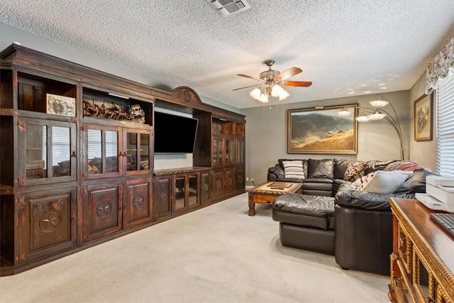 living room with ceiling fan, light colored carpet, and a textured ceiling