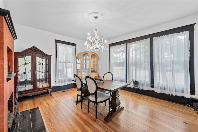 dining area with light wood-type flooring and a notable chandelier