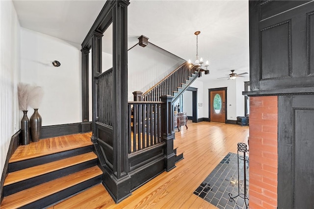 stairway featuring wood-type flooring and ceiling fan with notable chandelier