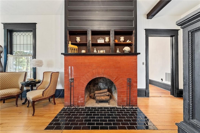 living area with beam ceiling, a fireplace, and hardwood / wood-style floors