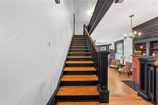 stairway with wood-type flooring and a chandelier