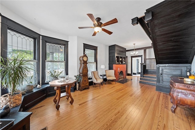 living room featuring ceiling fan with notable chandelier and light wood-type flooring