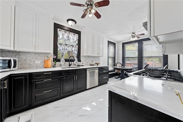 kitchen featuring white cabinetry, sink, ceiling fan, stainless steel appliances, and decorative backsplash