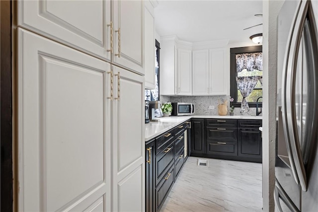 kitchen featuring decorative backsplash, white cabinets, and stainless steel appliances