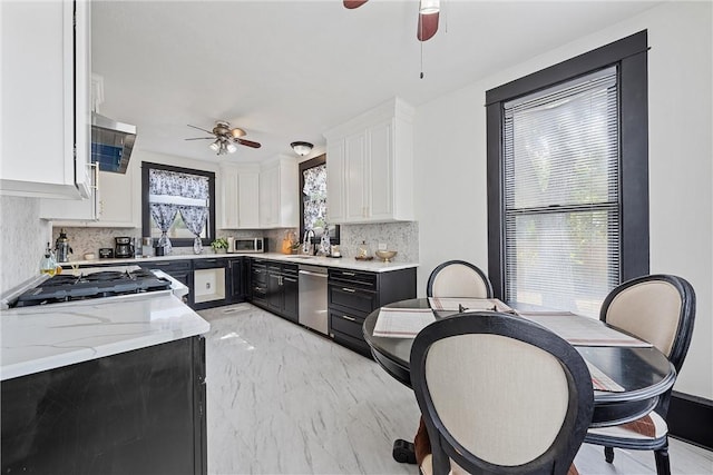 kitchen with backsplash, stainless steel appliances, white cabinetry, and sink