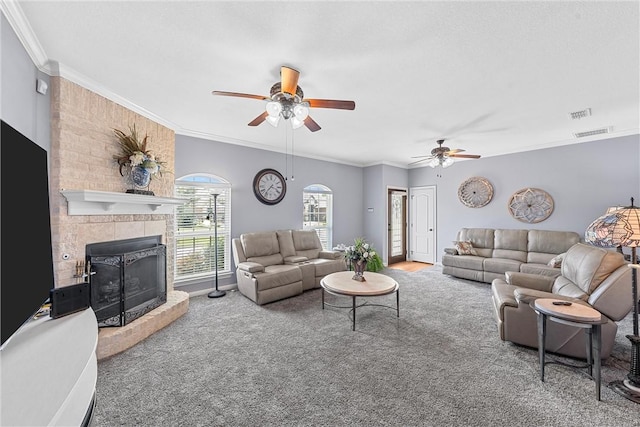 carpeted living room featuring a fireplace, ceiling fan, and crown molding