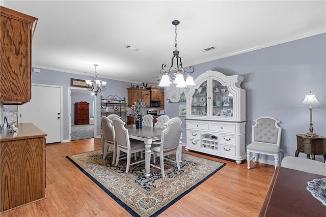 dining room with crown molding, light hardwood / wood-style floors, and an inviting chandelier