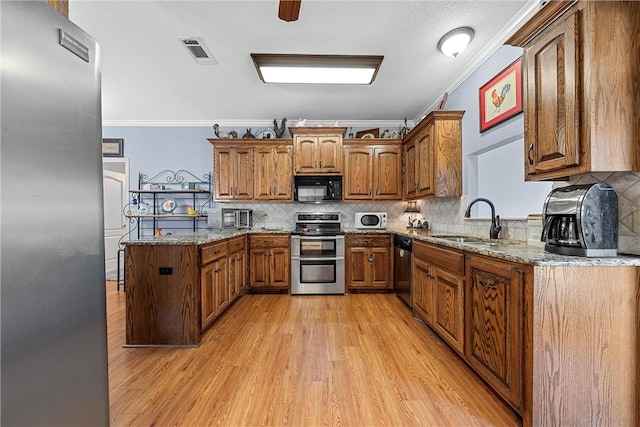 kitchen with appliances with stainless steel finishes, backsplash, crown molding, sink, and light hardwood / wood-style flooring