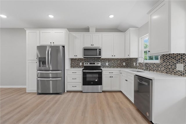 kitchen with decorative backsplash, stainless steel appliances, sink, white cabinets, and light hardwood / wood-style floors