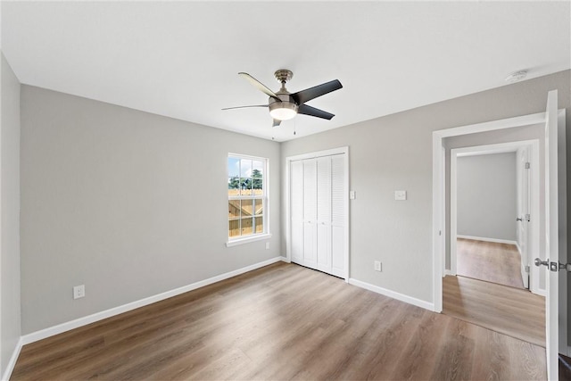 unfurnished bedroom featuring ceiling fan, a closet, and hardwood / wood-style flooring