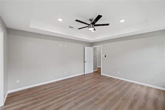 unfurnished room with hardwood / wood-style floors, ceiling fan, and a tray ceiling