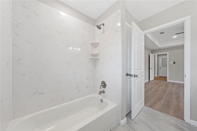 bathroom with hardwood / wood-style floors and tiled shower / bath