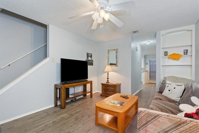 living room featuring ceiling fan, hardwood / wood-style floors, and a textured ceiling